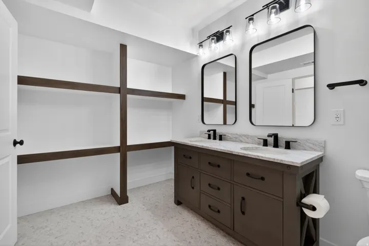 Double vanity featuring a light-toned countertop, dual sinks with matte black faucets, and rectangular mirrors with black frames