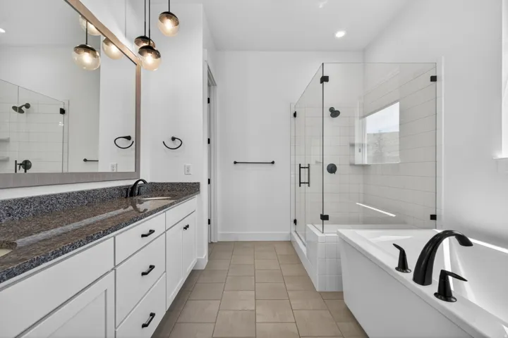 Double vanity with dark granite countertops, white cabinetry, and matte black hardware