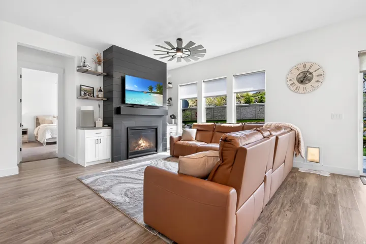 Wood-finish flooring throughout, complemented by a contemporary fireplace with dark shiplap detailing and a hearth