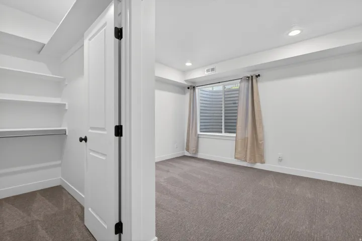 Bedroom featuring recessed lighting, a window with a window well, and neutral carpeting