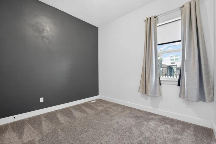 Room featuring a dark accent wall, plush carpet flooring, and a window with white trim
