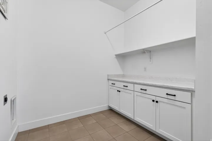 White cabinetry with black hardware, a white countertop, and open shelving