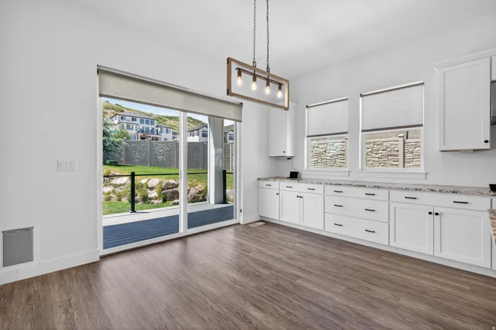 Contemporary kitchen area featuring wood-finish flooring, white cabinetry with dark hardware, and light-toned countertops