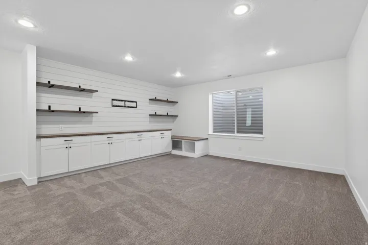 Spacious room featuring a wall of shiplap accenting built-in cabinetry, open shelving, and a built-in bench