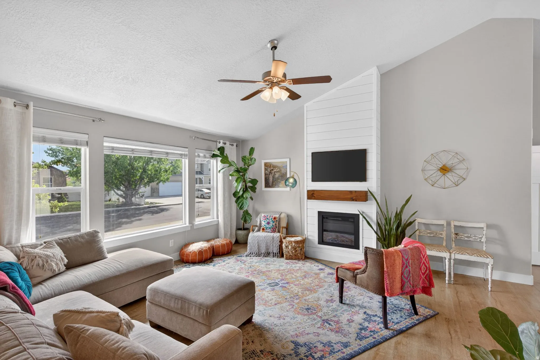 Living room featuring wood finished floors, ceiling fan, and a large fireplace