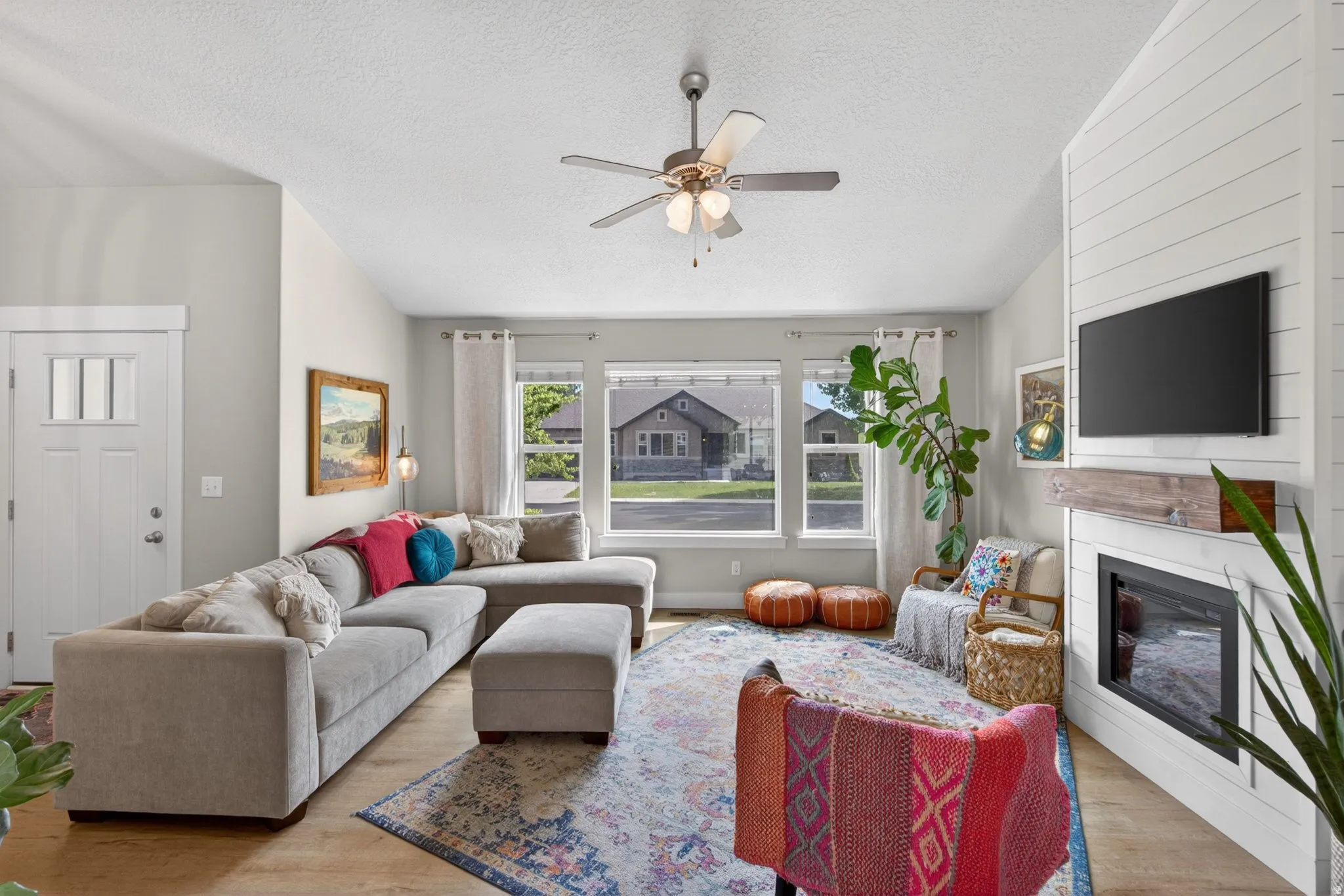 Living room featuring wood finished floors, a ceiling fan, and a glass covered fireplace