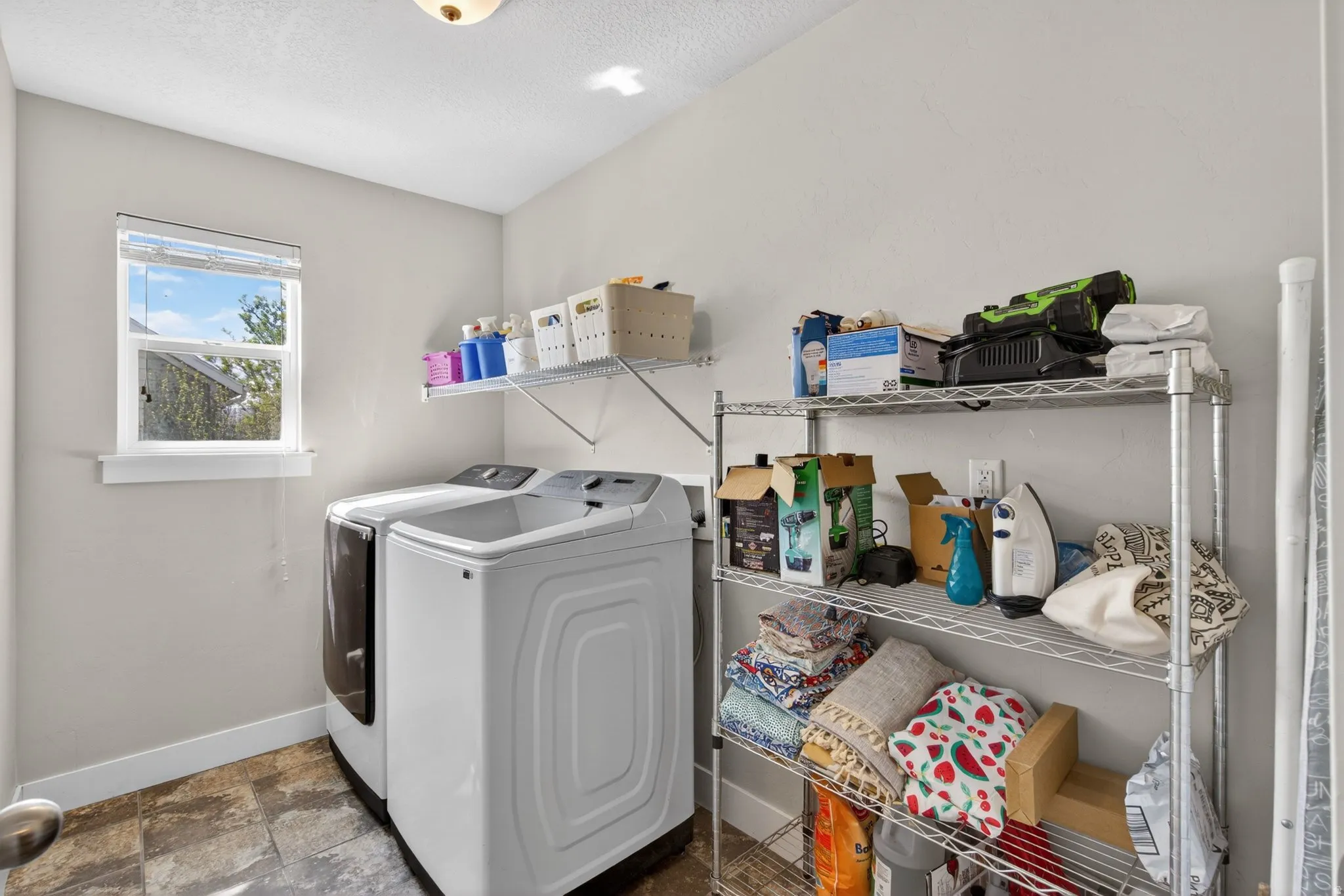 Laundry area featuring stone finish flooring, washer and dryer, and a textured ceiling