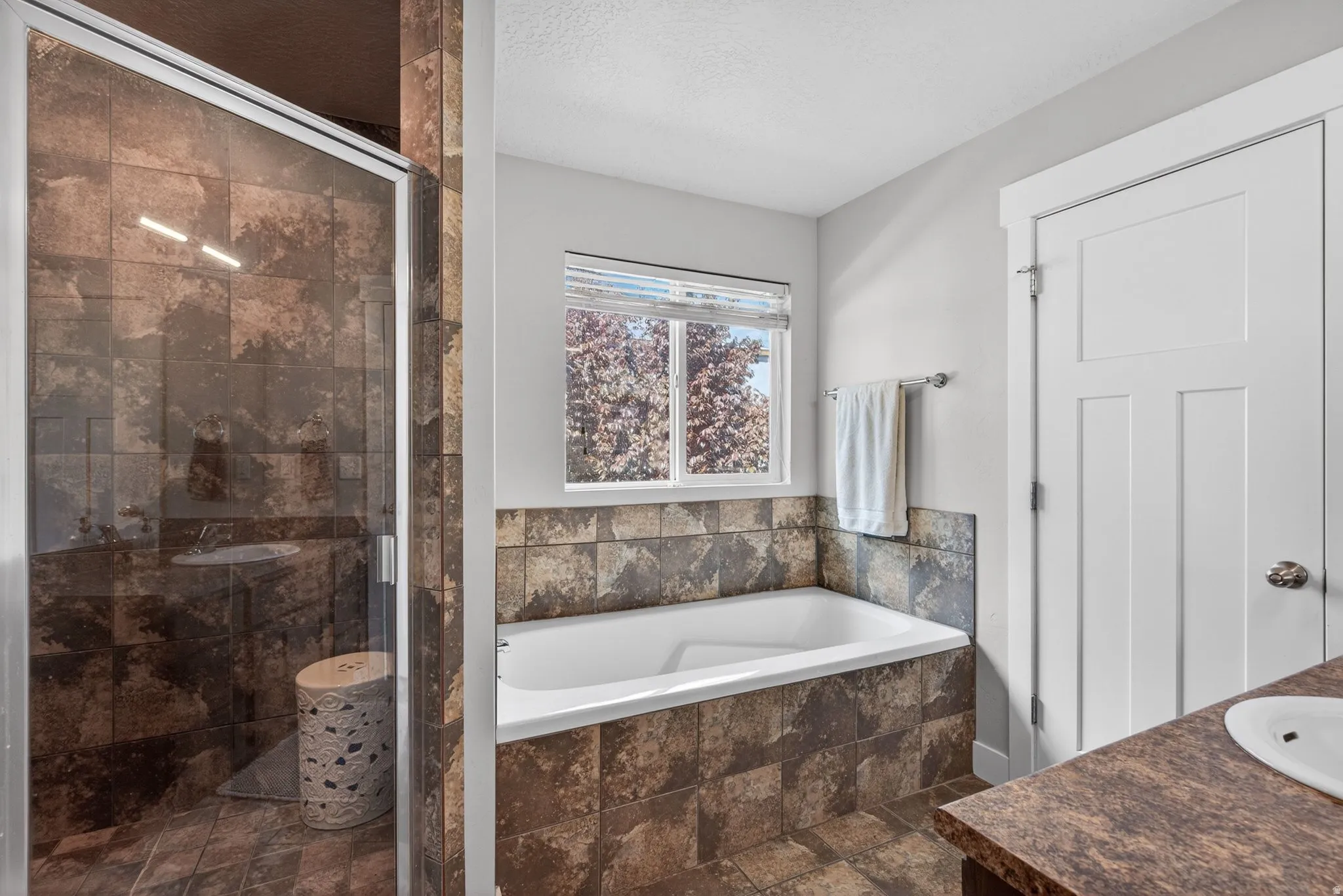 Full bath with a stall shower, a garden tub, vanity, and a textured ceiling