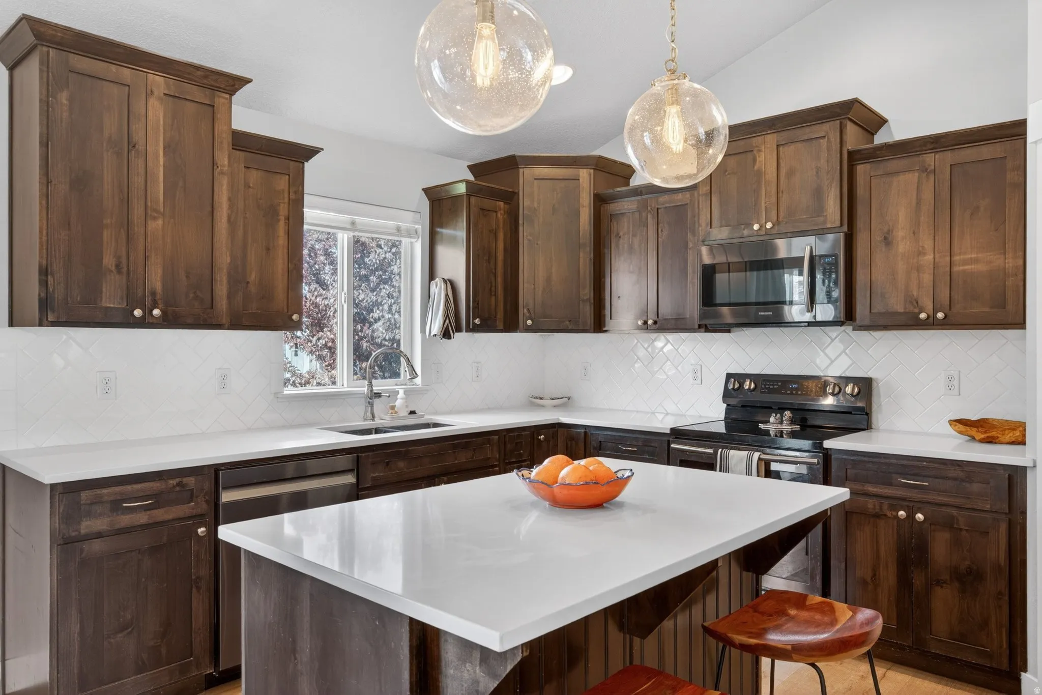Kitchen featuring dark wood finish cabinets, stainless steel appliances, a kitchen bar, a kitchen island, and lofted ceiling