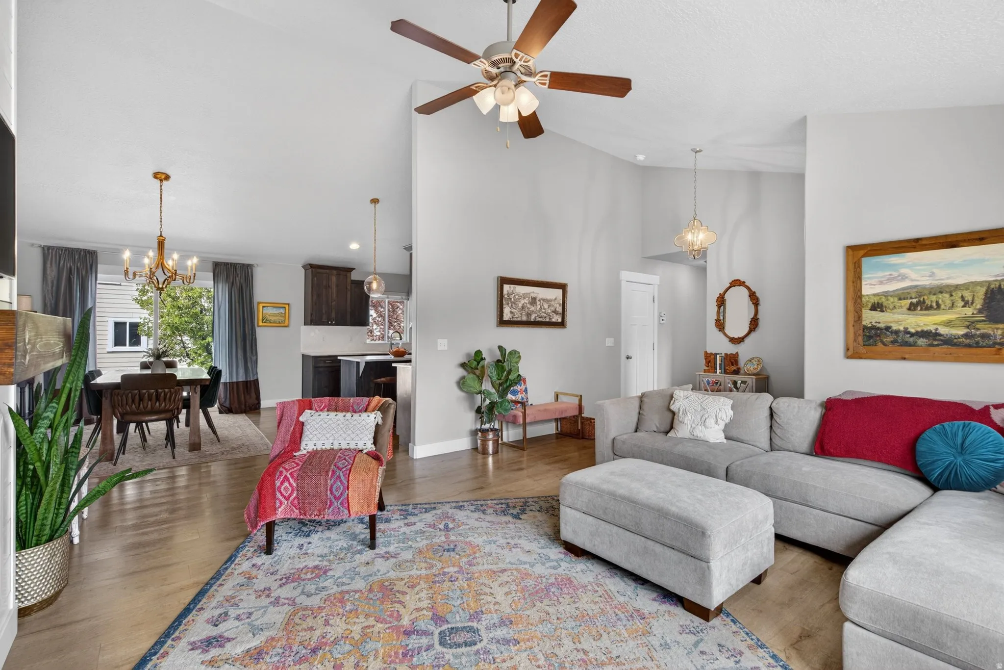 Living area with a chandelier, ceiling fan, wood finished floors, and lofted ceiling