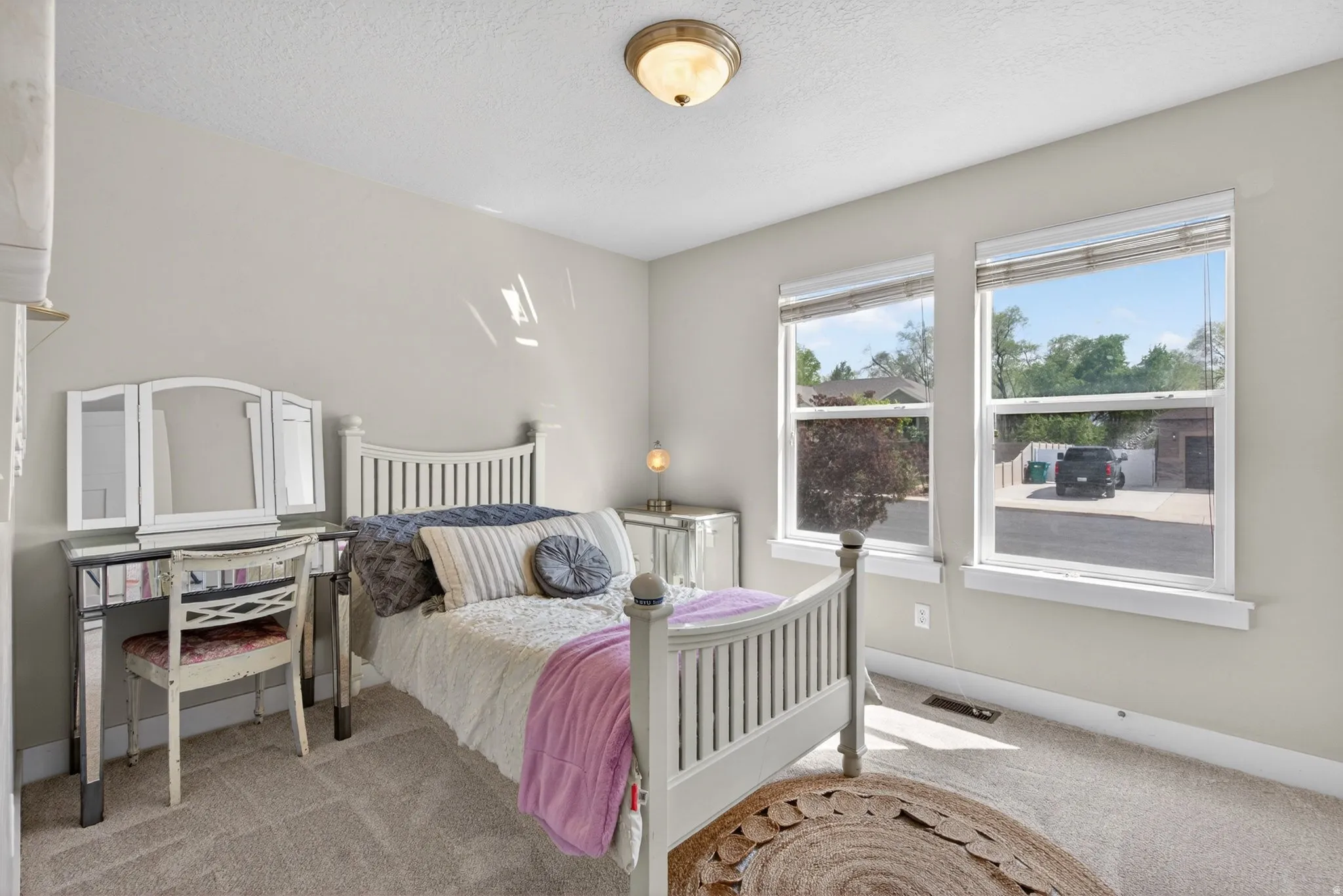 Bedroom with light colored carpet and a textured ceiling