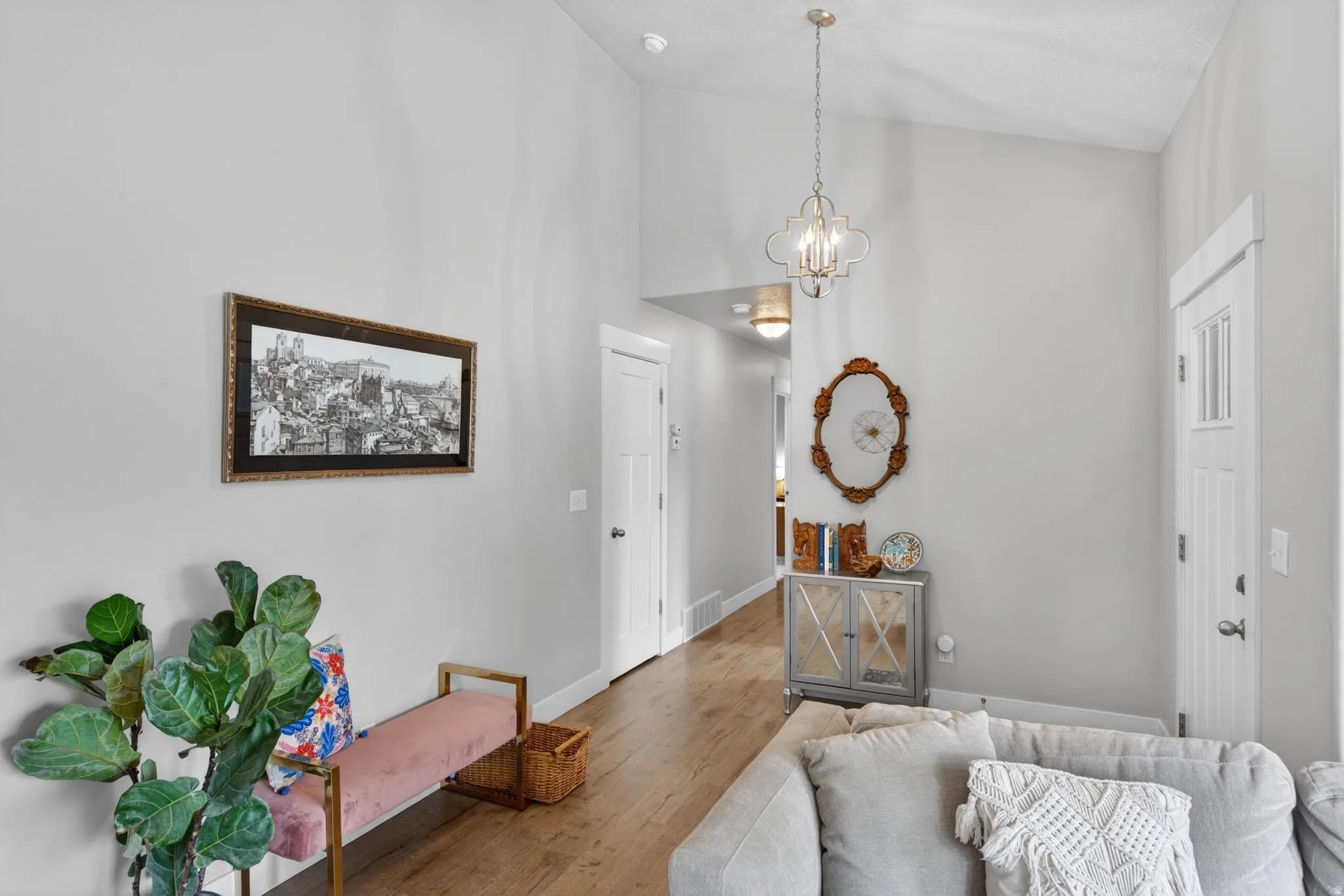 Entryway with hanging lights, wood finished floors, and vaulted ceiling