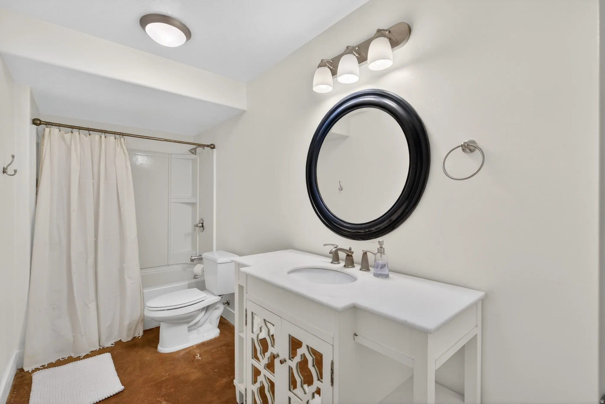 Bathroom with vanity, finished concrete floors, and shower / tub combo
