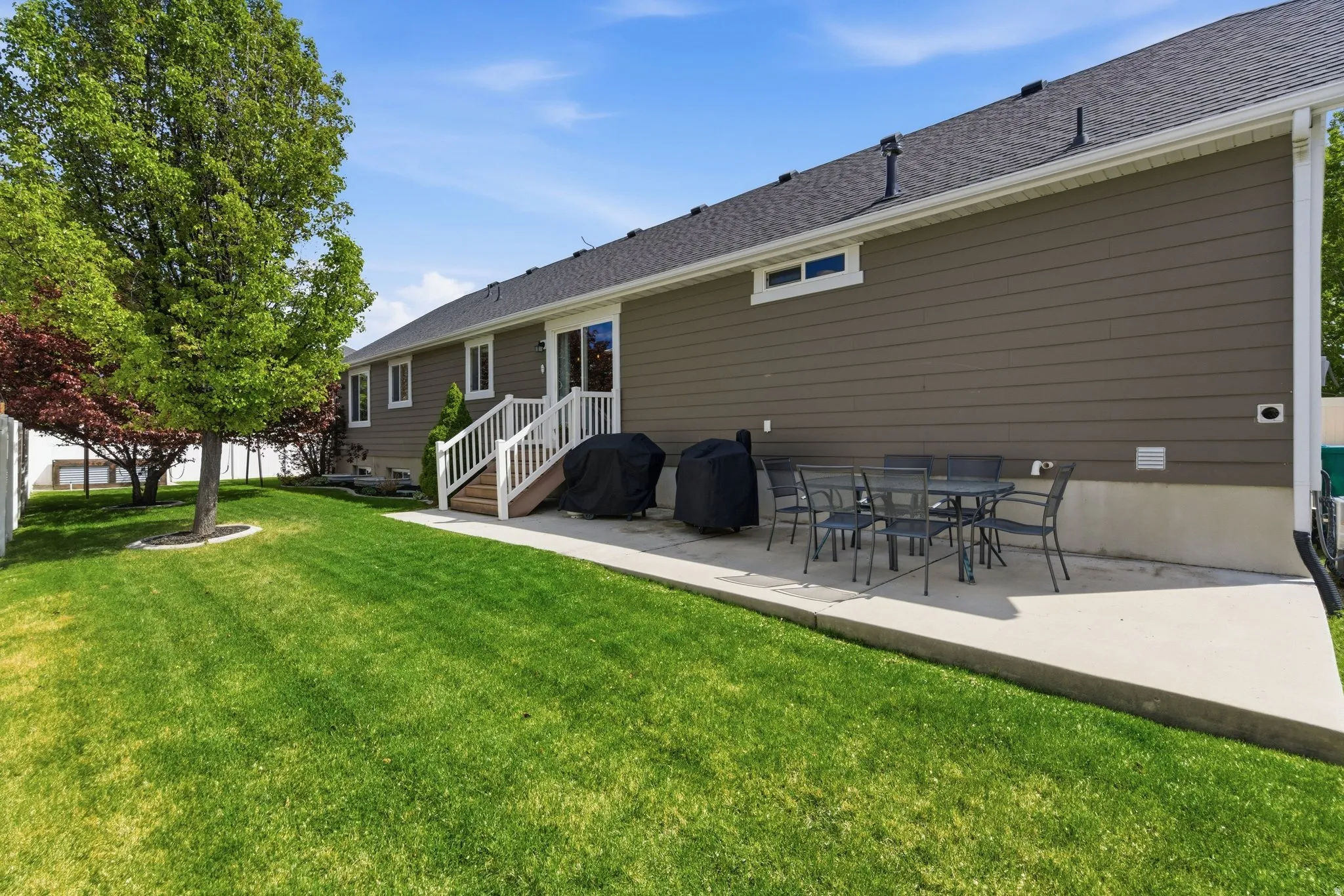 Rear view of house featuring a patio area, a lawn, a shingled roof, and outdoor dining space