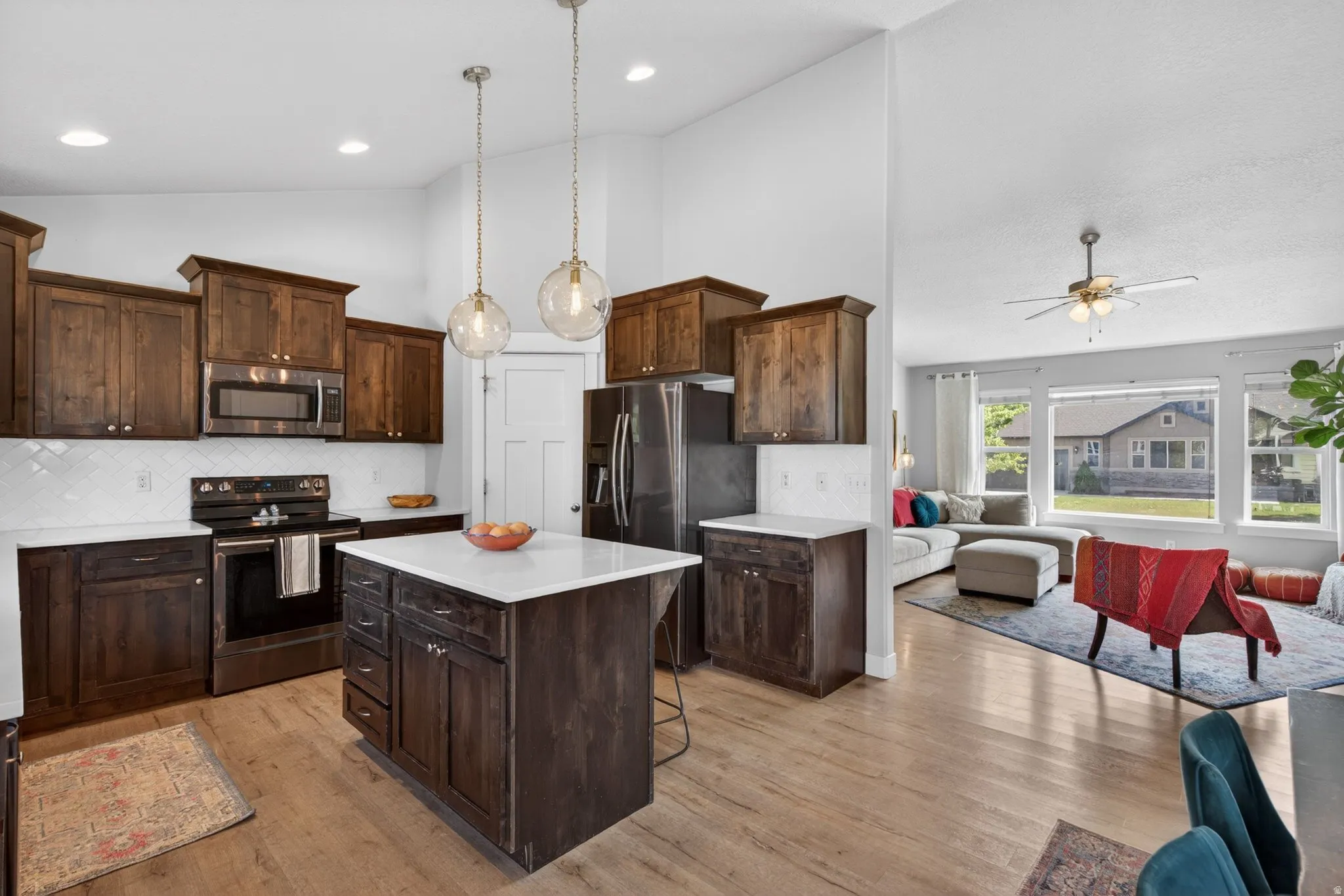 Kitchen featuring stainless steel appliances, light wood finished floors, tasteful backsplash, a center island, and dark wood finish cabinets