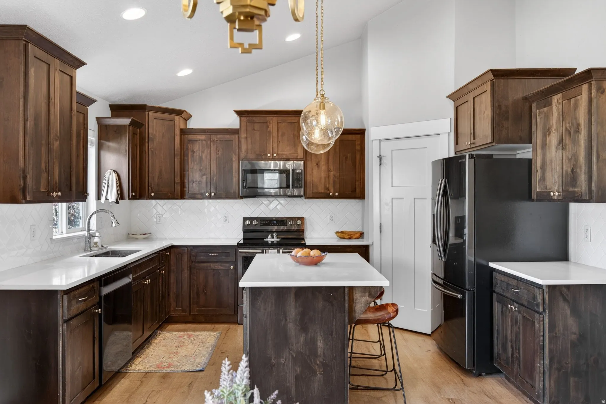 Kitchen featuring dark wood finish cabinetry, stainless steel appliances, a center island, vaulted ceiling, and decorative backsplash