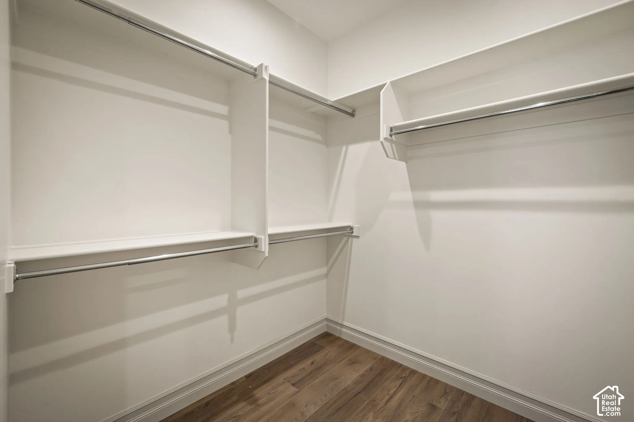 Walk in closet with dark wood-style flooring