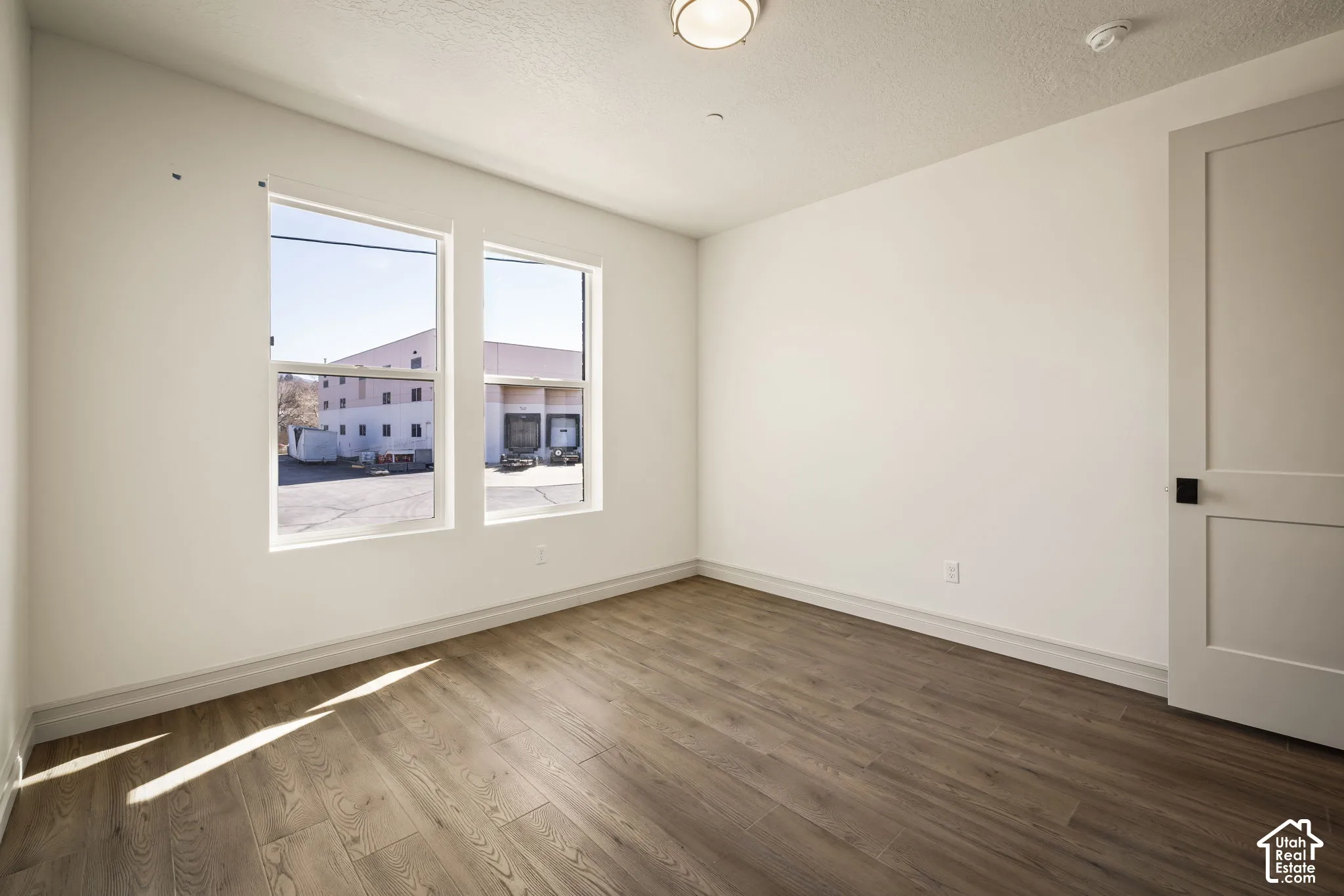 Empty room featuring dark wood-style flooring and a textured ceiling