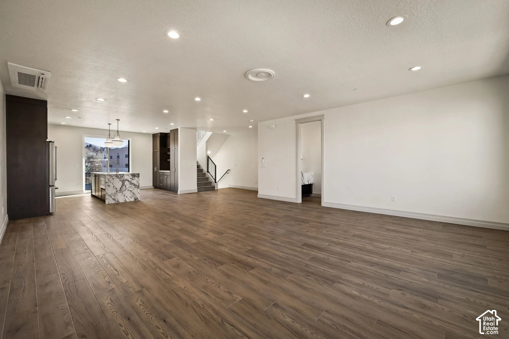 Unfurnished living room featuring dark wood-style flooring, recessed lighting, and a textured ceiling