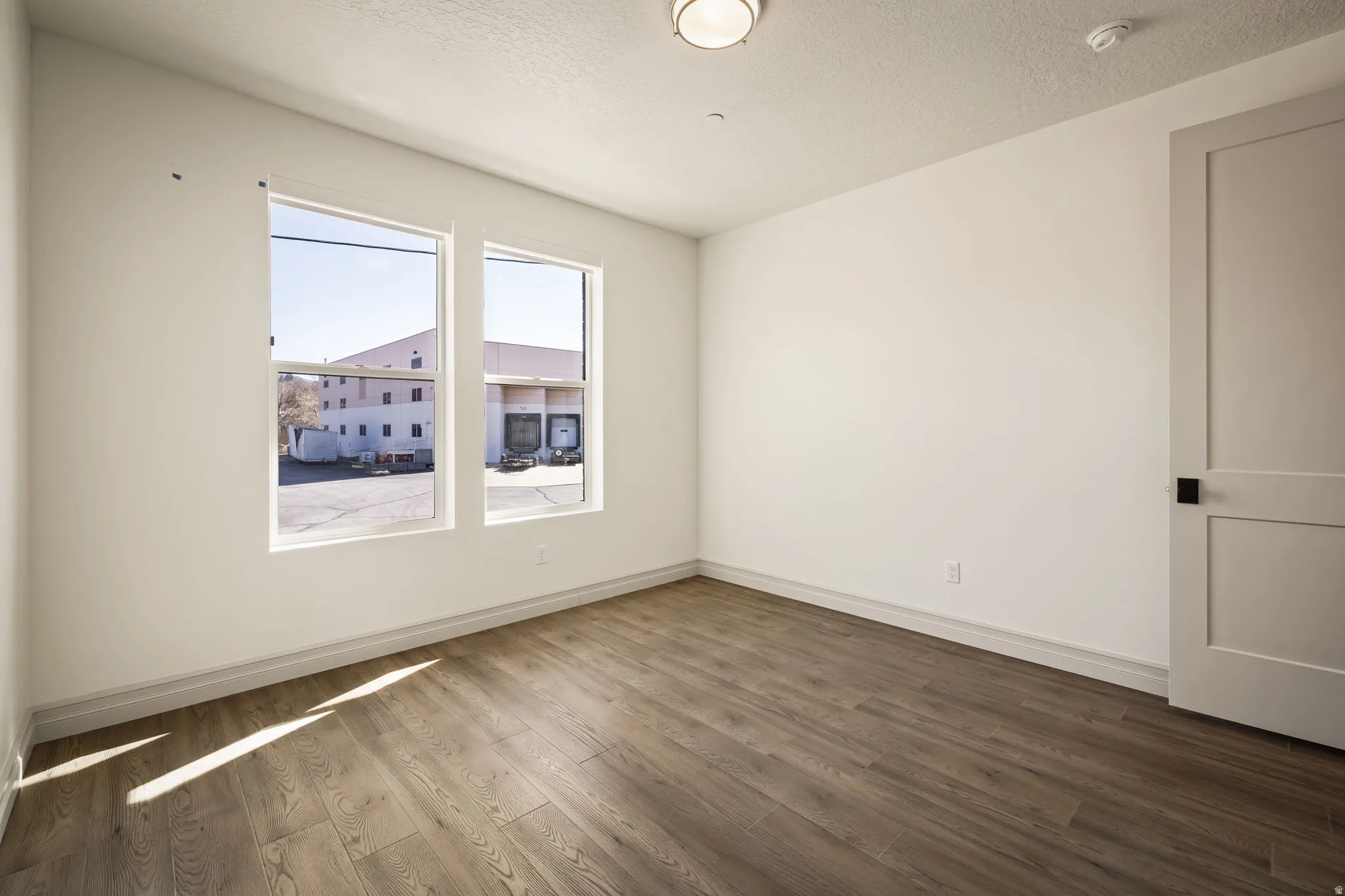 Empty room featuring dark wood-style flooring and a textured ceiling