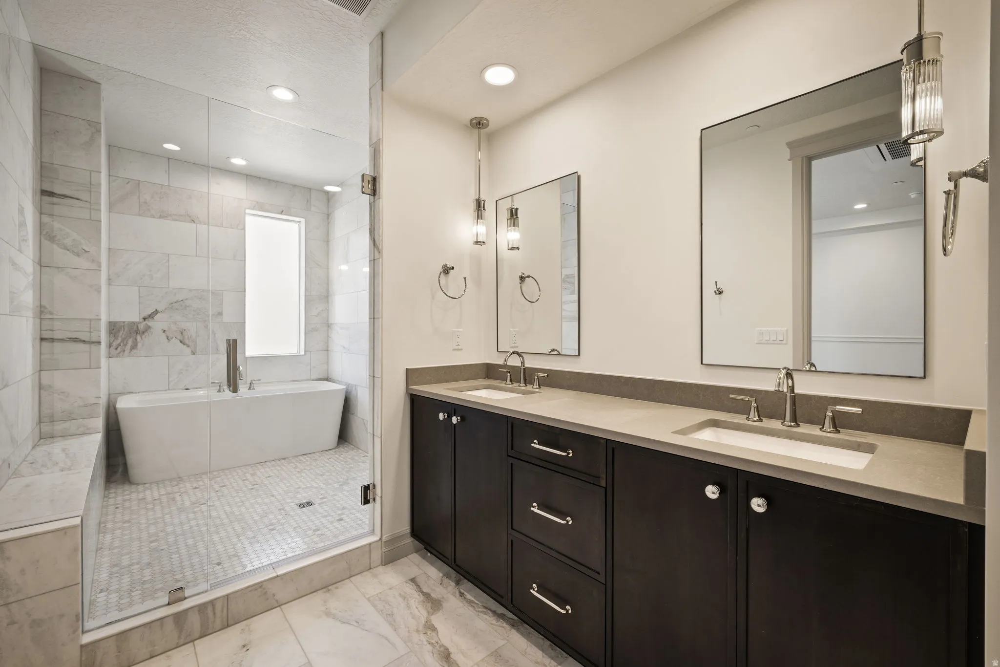 Full bath featuring double vanity, recessed lighting, a freestanding bath, light marble finish floors, and a stall shower