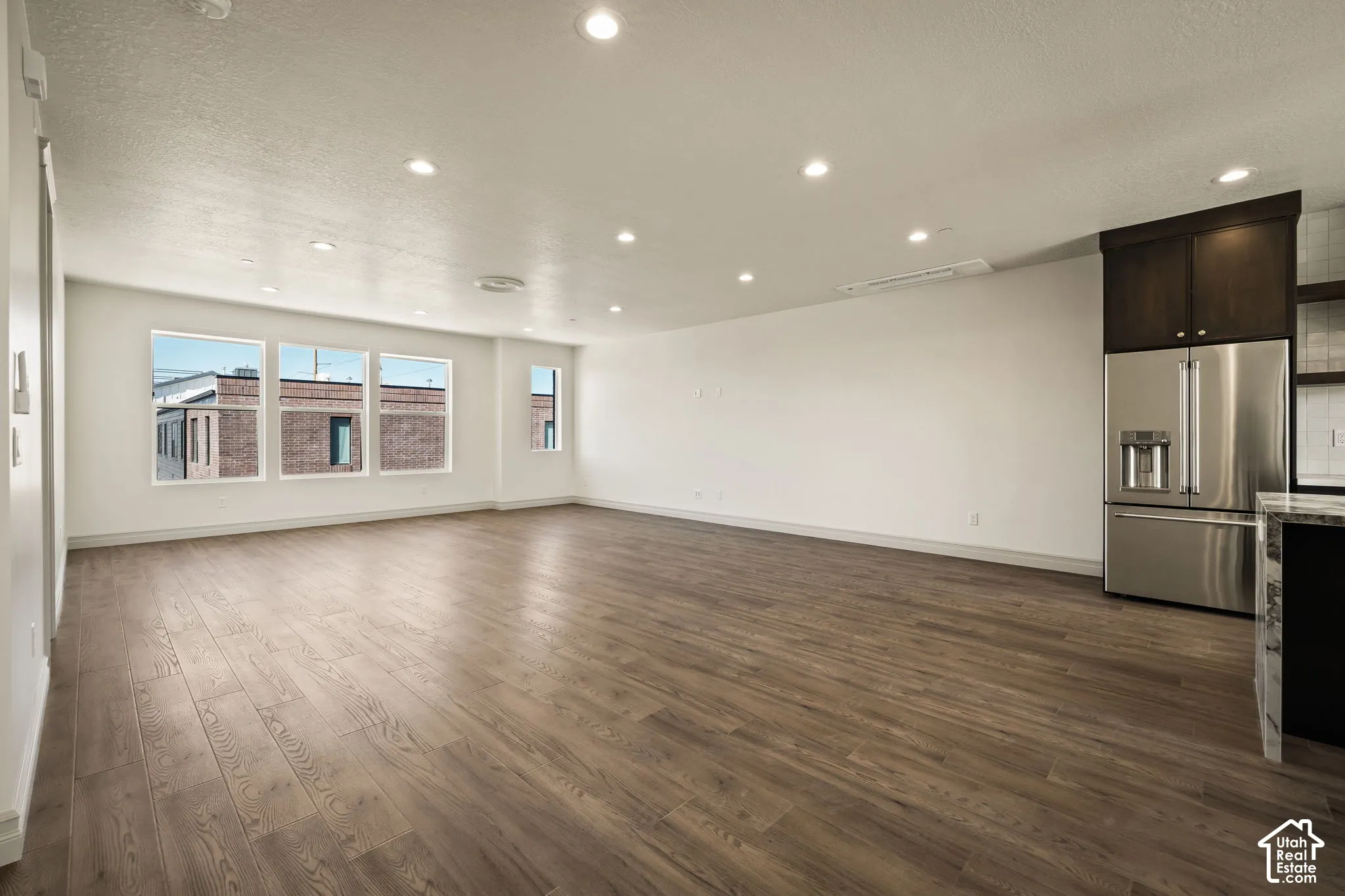 Unfurnished living room featuring dark wood-style flooring, recessed lighting, and a textured ceiling