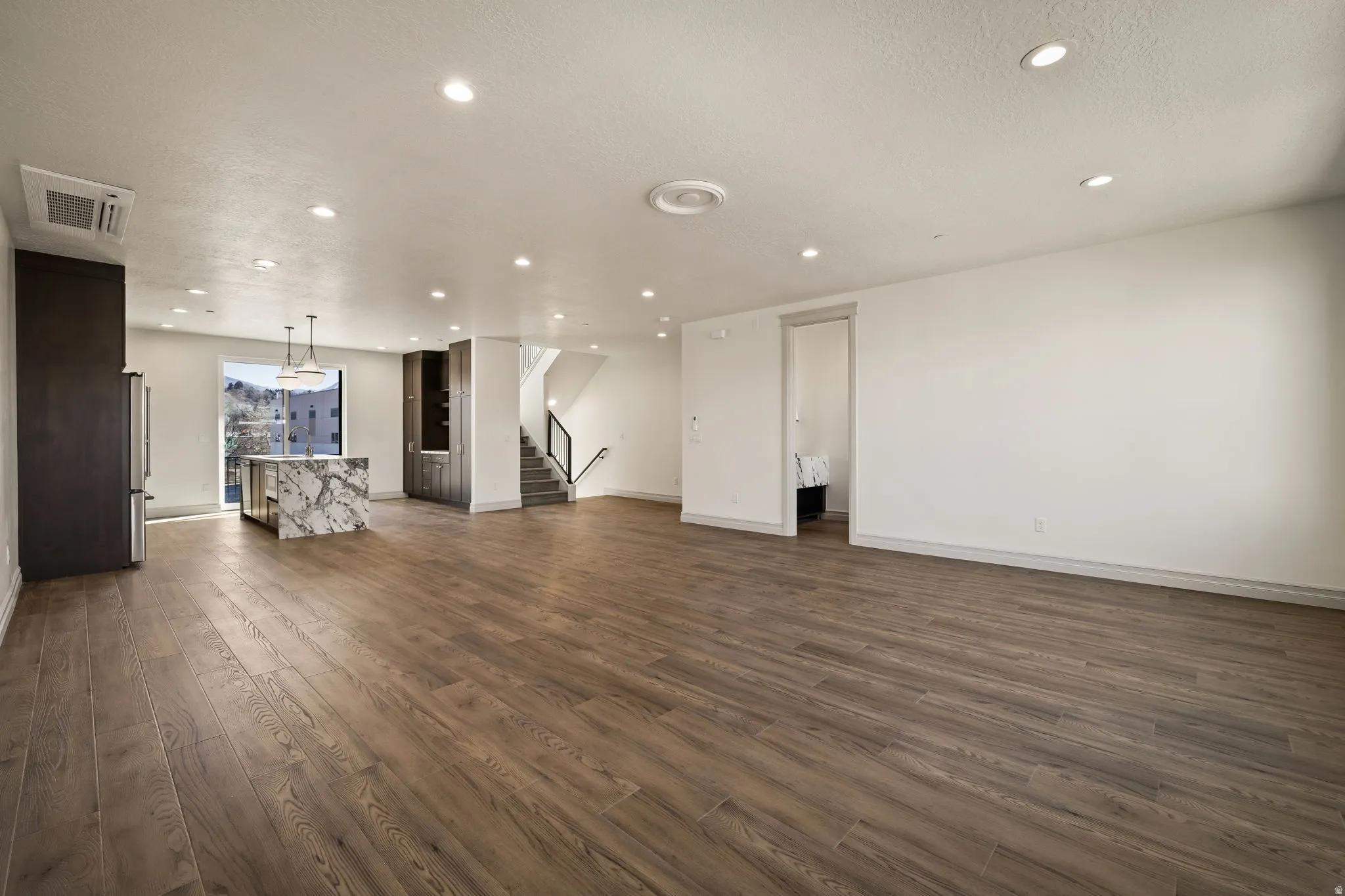 Unfurnished living room featuring dark wood-style flooring, recessed lighting, and a textured ceiling