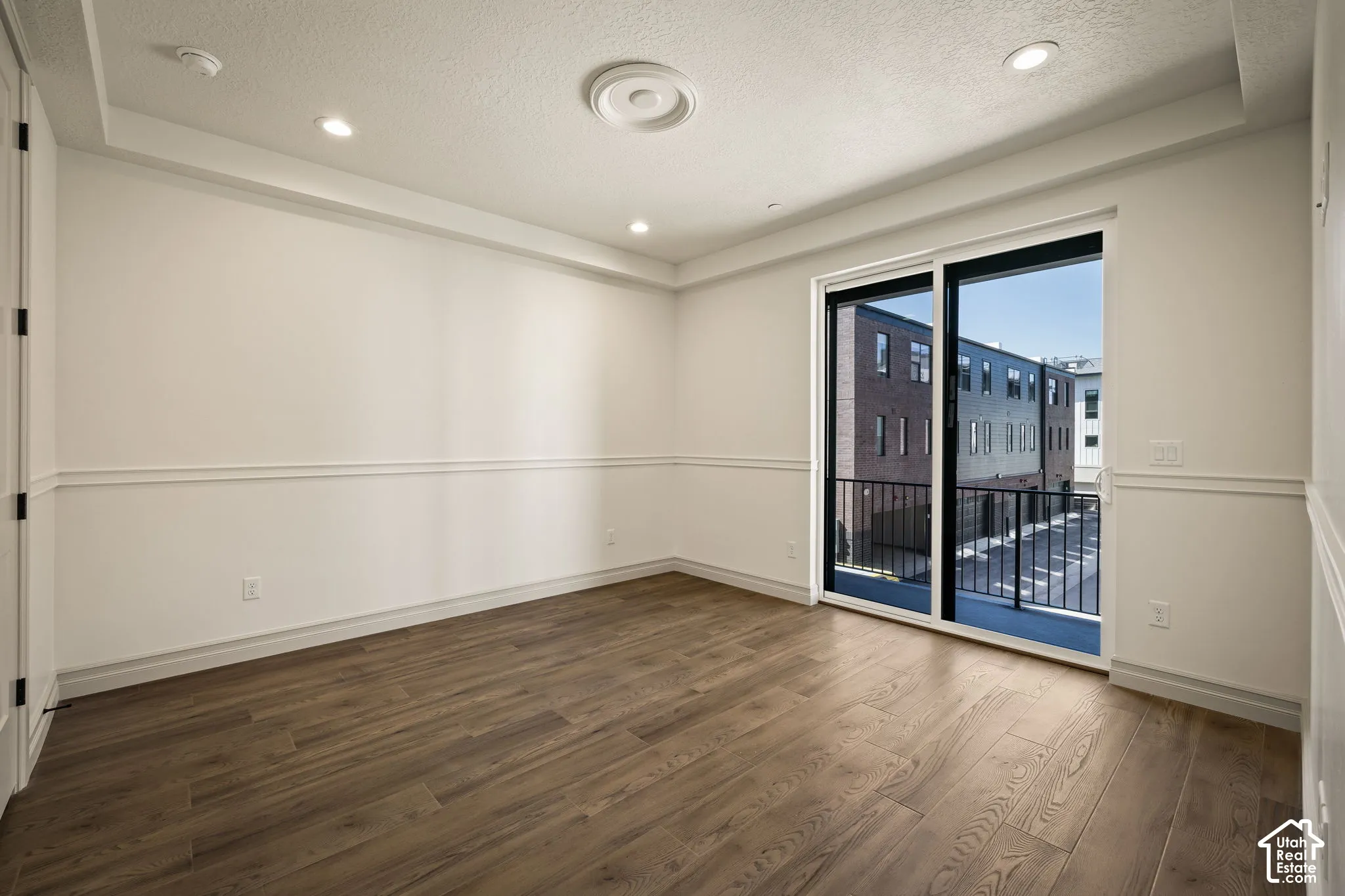 Spare room with dark wood-type flooring, a textured ceiling, and recessed lighting