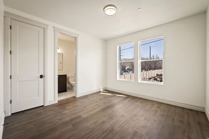 Unfurnished bedroom featuring ensuite bath and dark wood-type flooring