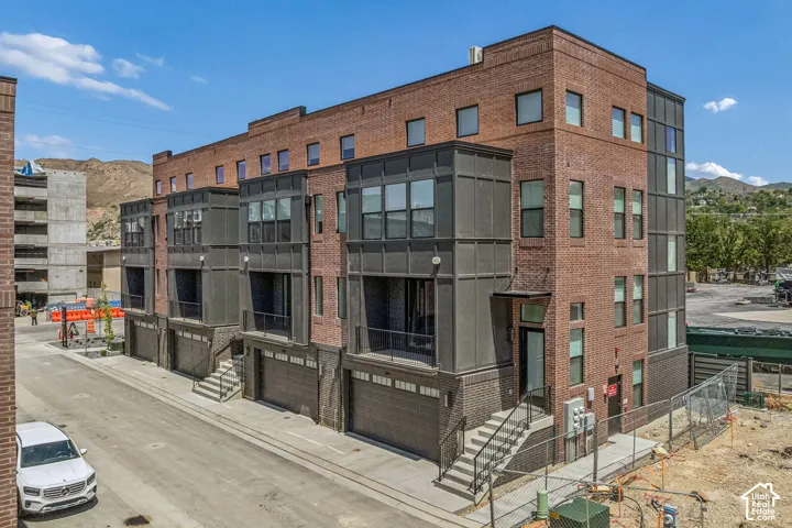Contemporary townhome architecture featuring a brick facade, integrated garage access, and private balconies