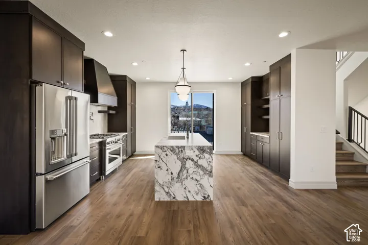 Kitchen featuring premium appliances, light stone counters, and dark wood finish cabinetry