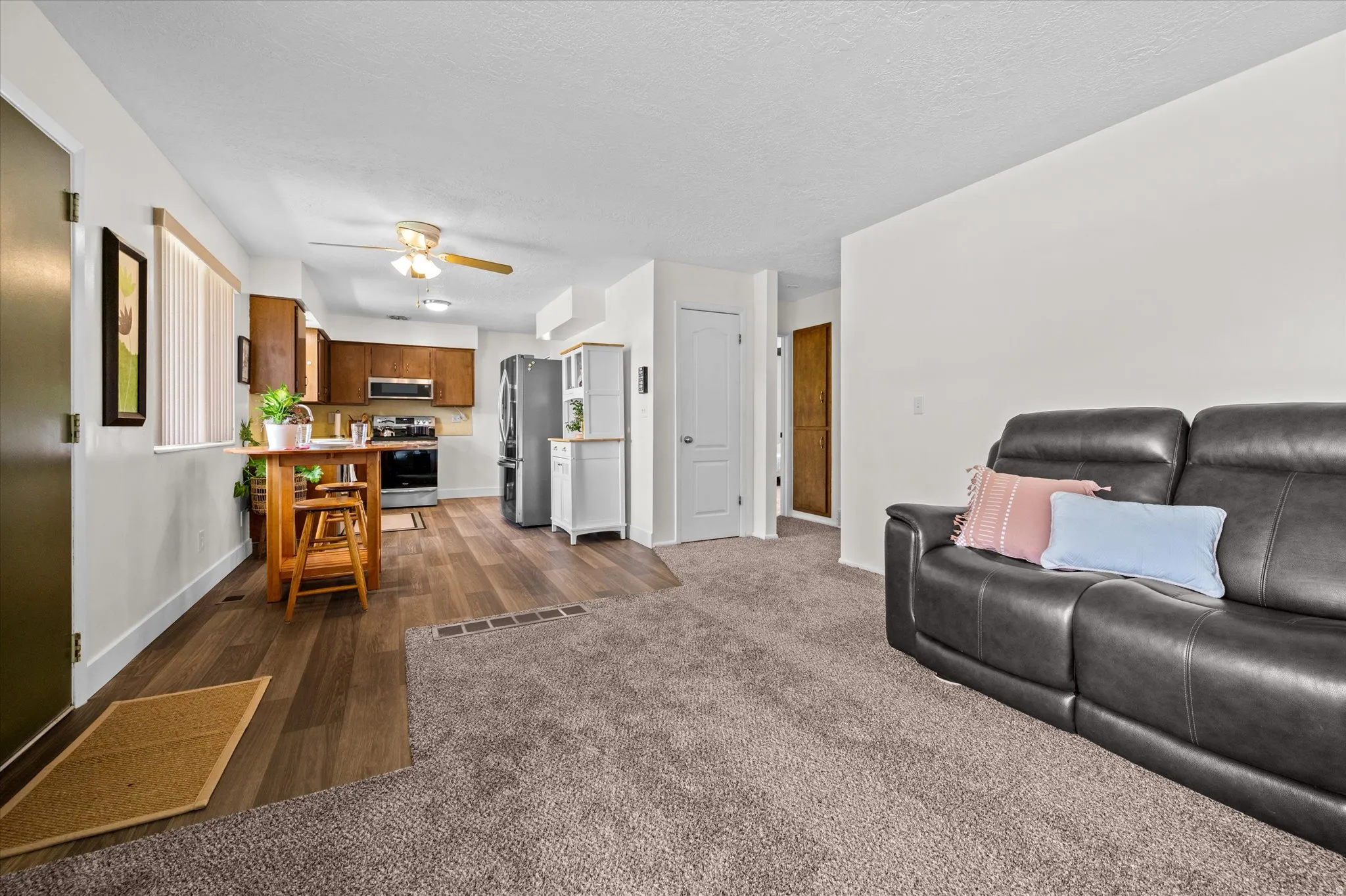 Living area with dark wood-style floors, ceiling fan, dark colored carpet, and a textured ceiling