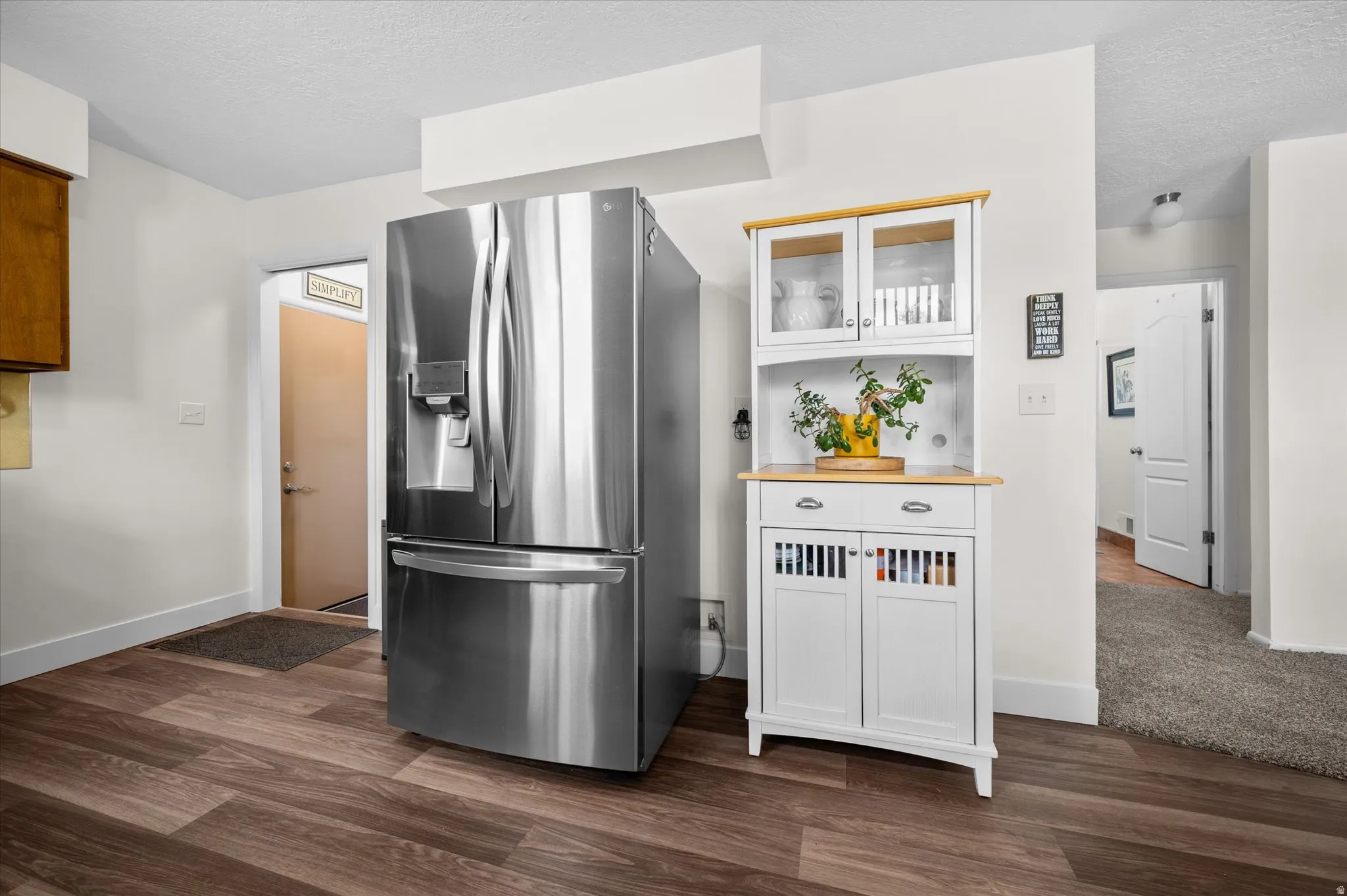 Kitchen featuring glass insert cabinets, stainless steel fridge with ice dispenser, a textured ceiling, white cabinetry, and dark wood finished floors