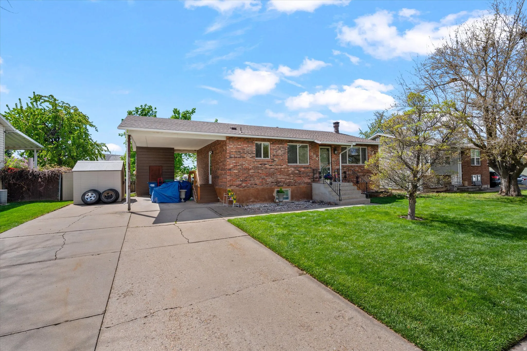 Single story home featuring brick siding, a front yard, a carport, and driveway