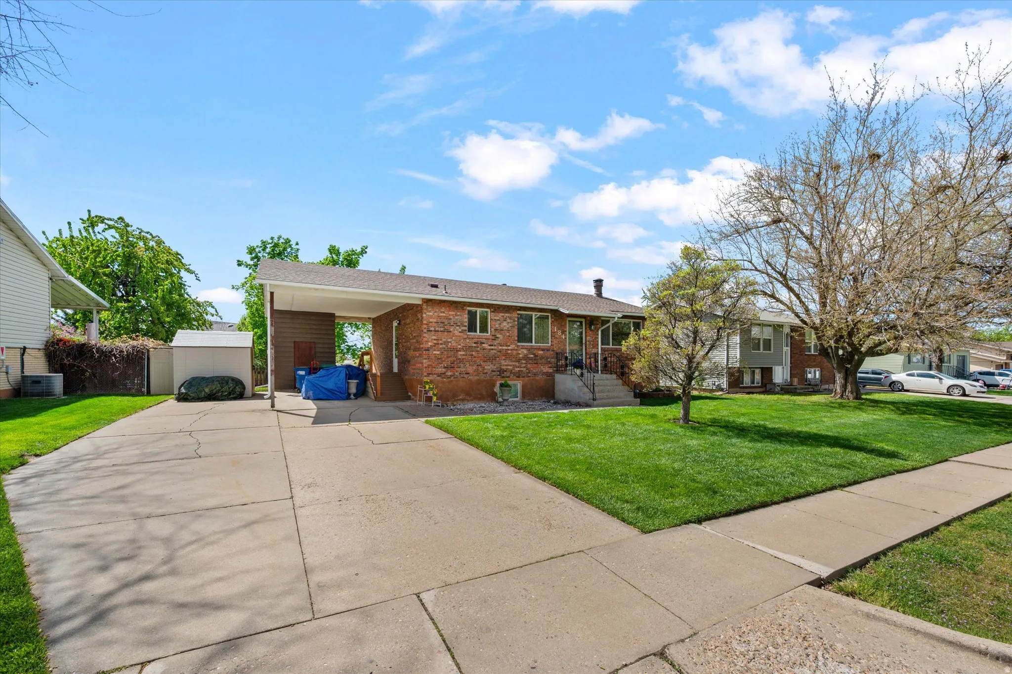 Ranch-style house featuring a front lawn, an attached carport, brick siding, and concrete driveway