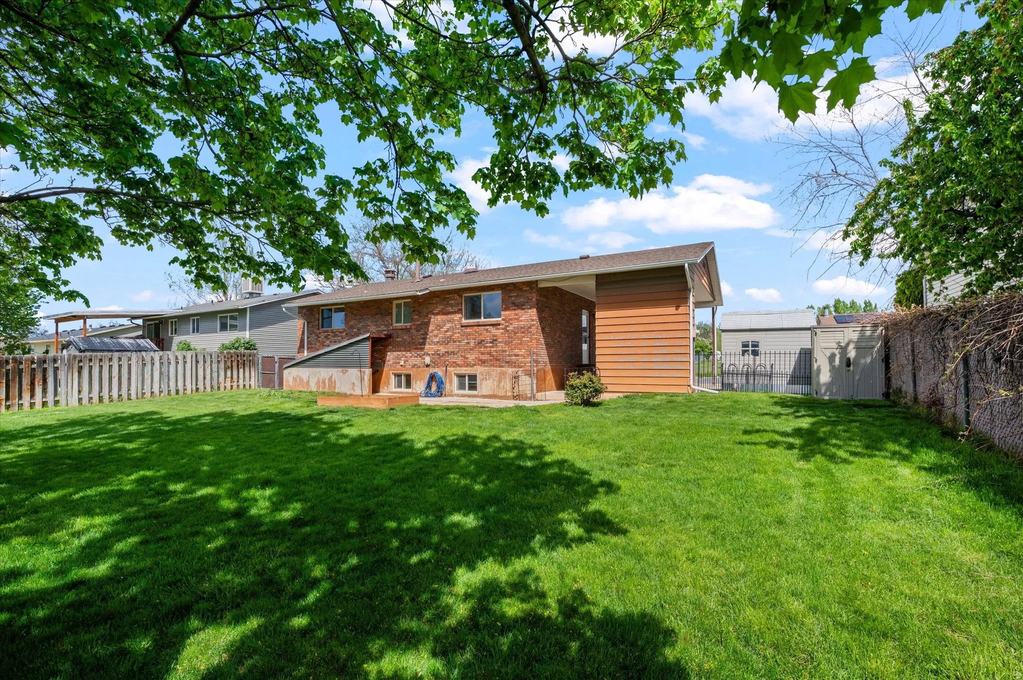 Back of property featuring a fenced backyard, brick siding, and a patio area