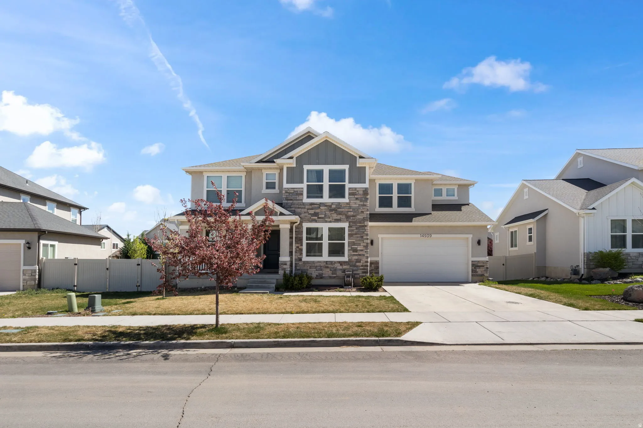 Craftsman inspired home featuring a gate, stone siding, driveway, board and batten siding, and an attached garage