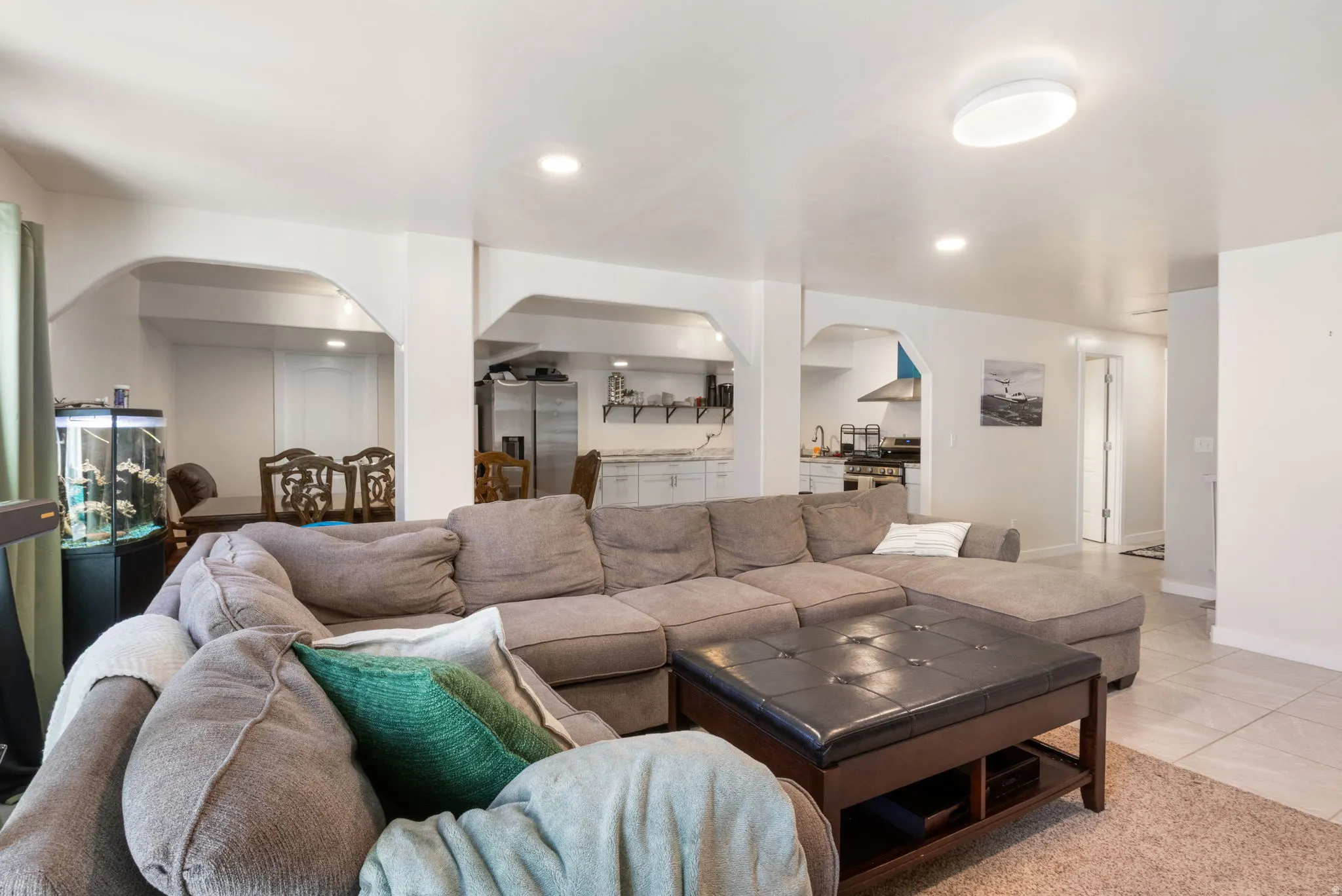Living room with arched walkways, light tile patterned flooring, and recessed lighting