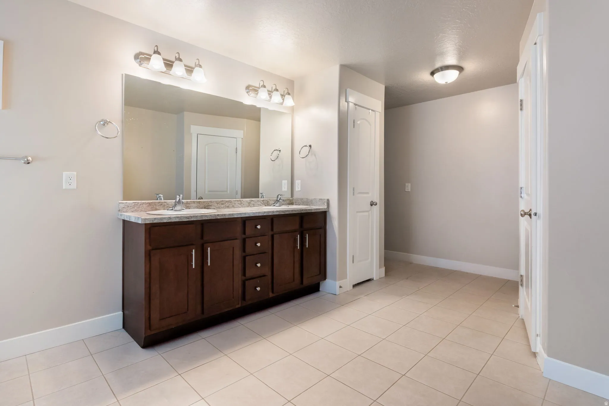 Bathroom with double vanity, light tile patterned floors, and a closet
