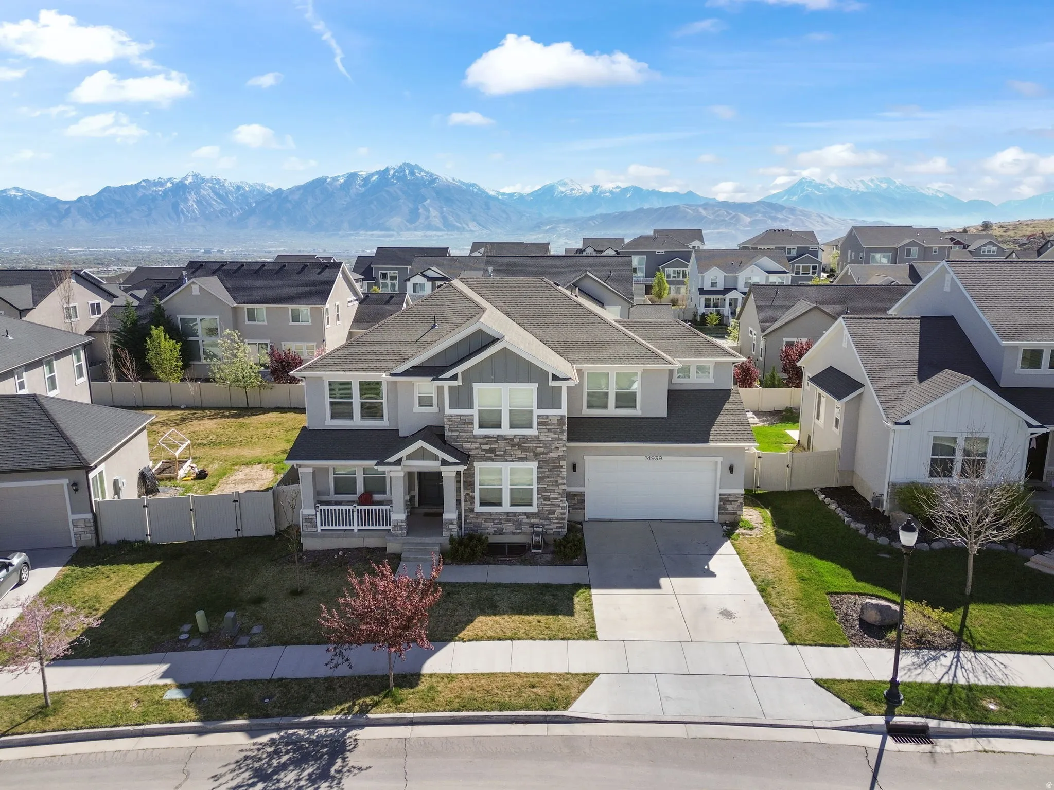 View of front of house featuring stone siding, a gate, driveway, a residential view, and a mountain view