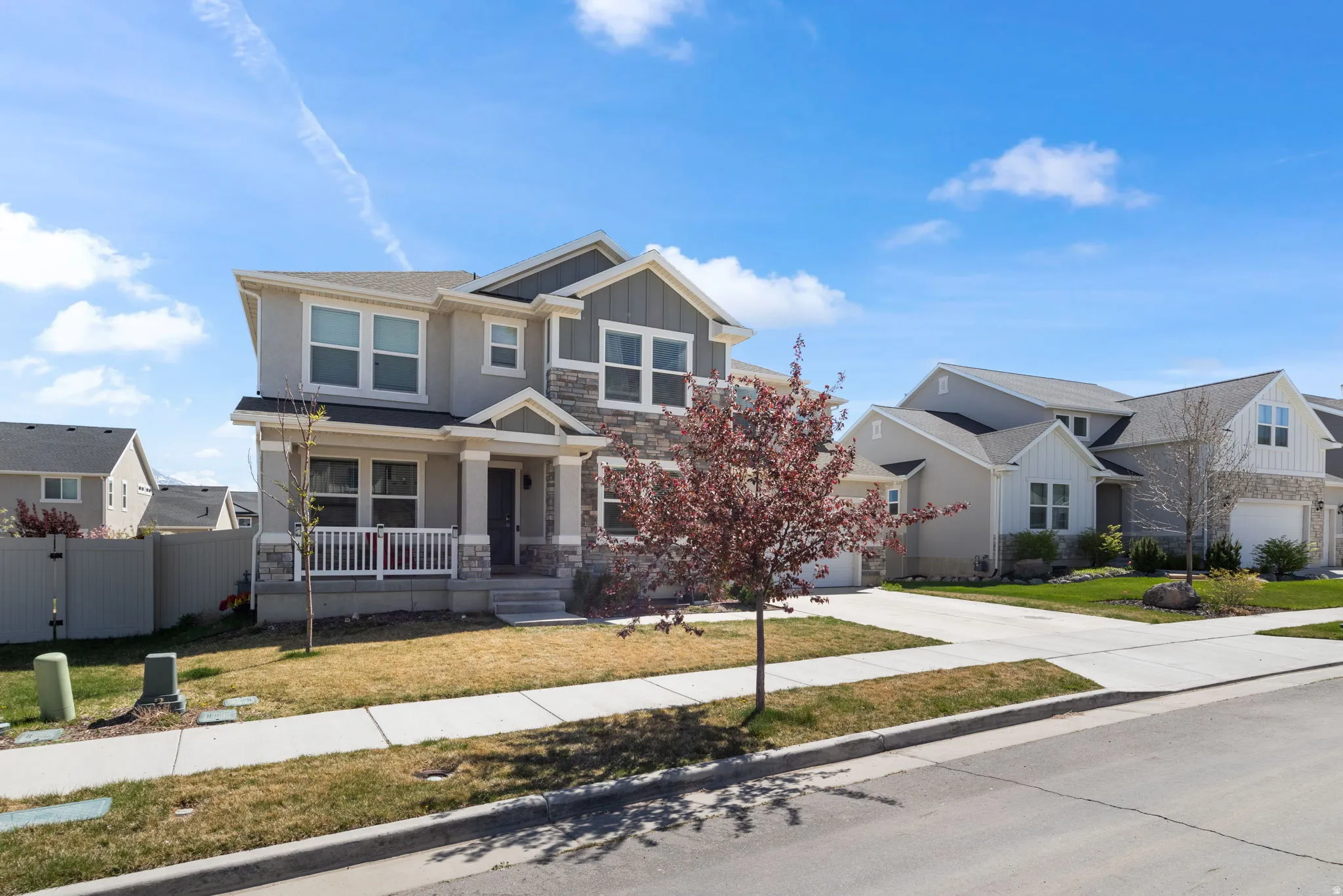Craftsman house featuring board and batten siding, stone siding, covered porch, and a front lawn