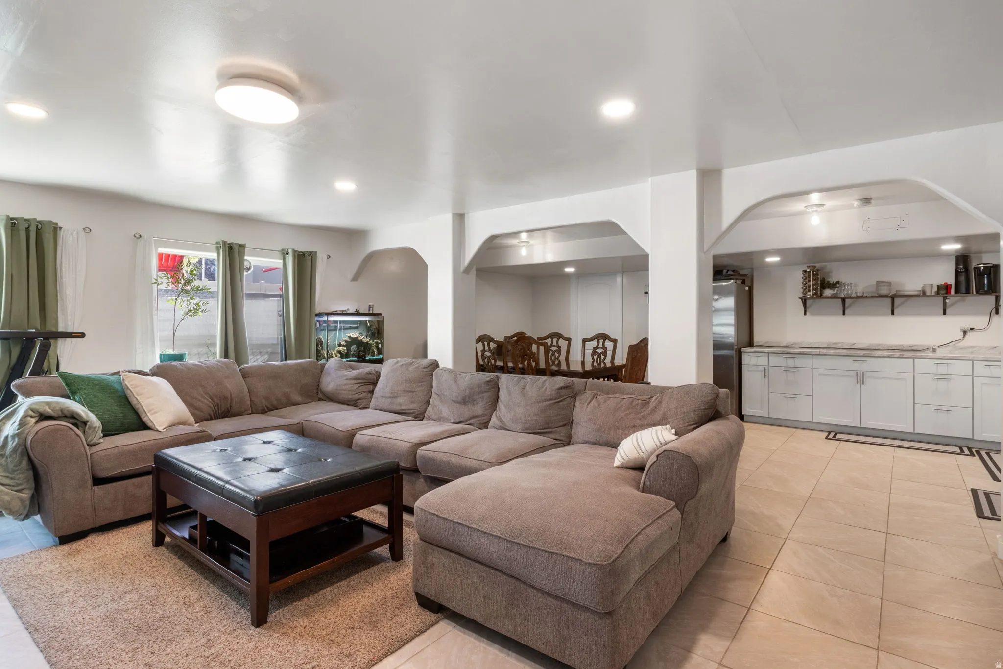 Living room with arched walkways, recessed lighting, and light tile patterned floors