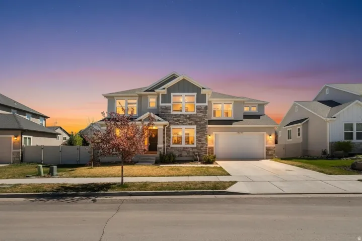 Craftsman house featuring stone siding, a gate, concrete driveway, board and batten siding, and a garage