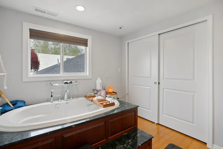 Bathroom featuring a garden tub, light wood-type flooring, and recessed lighting
