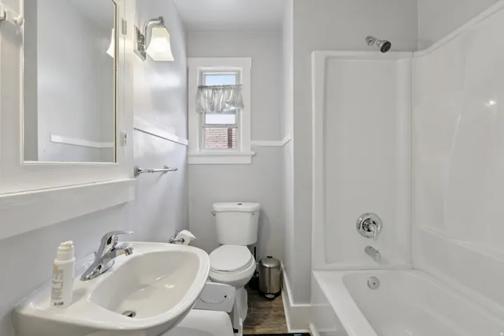 Full bathroom with tub / shower combination and dark wood-style flooring