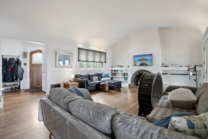 Living room featuring a barrel ceiling, wood finished floors, and a fireplace with raised hearth