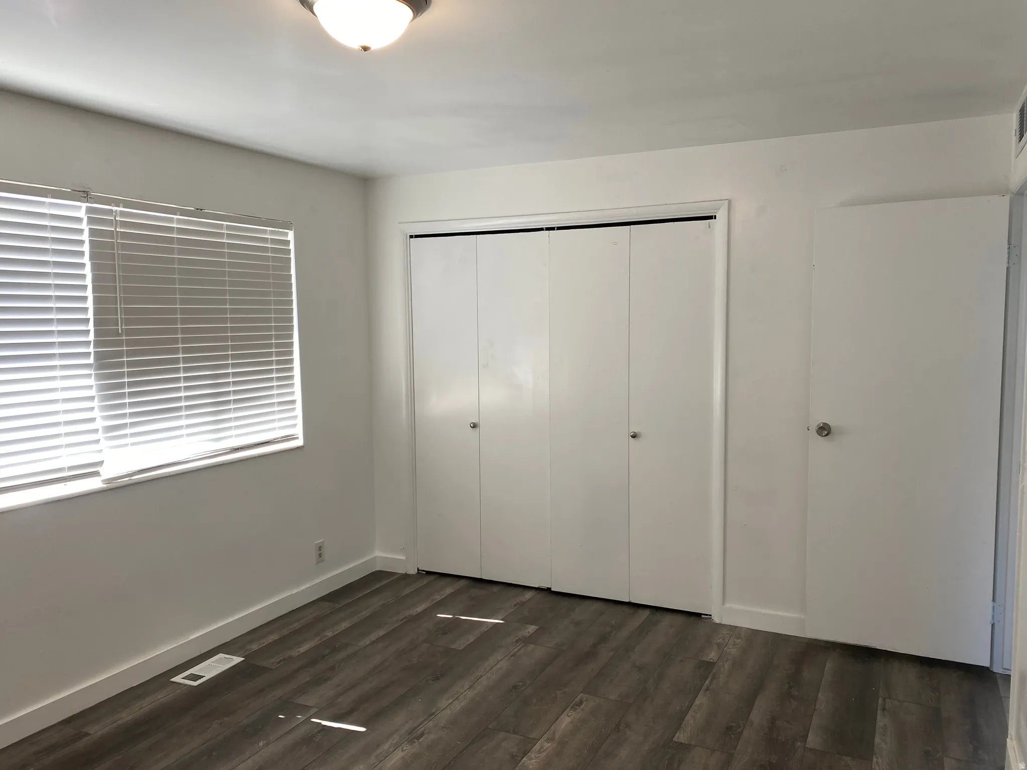 Unfurnished bedroom featuring dark wood-style flooring and a closet