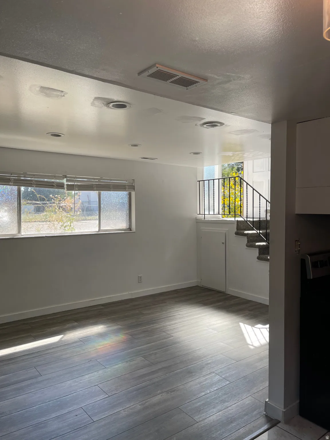 Unfurnished living room with dark wood-type flooring, plenty of natural light, and a textured ceiling
