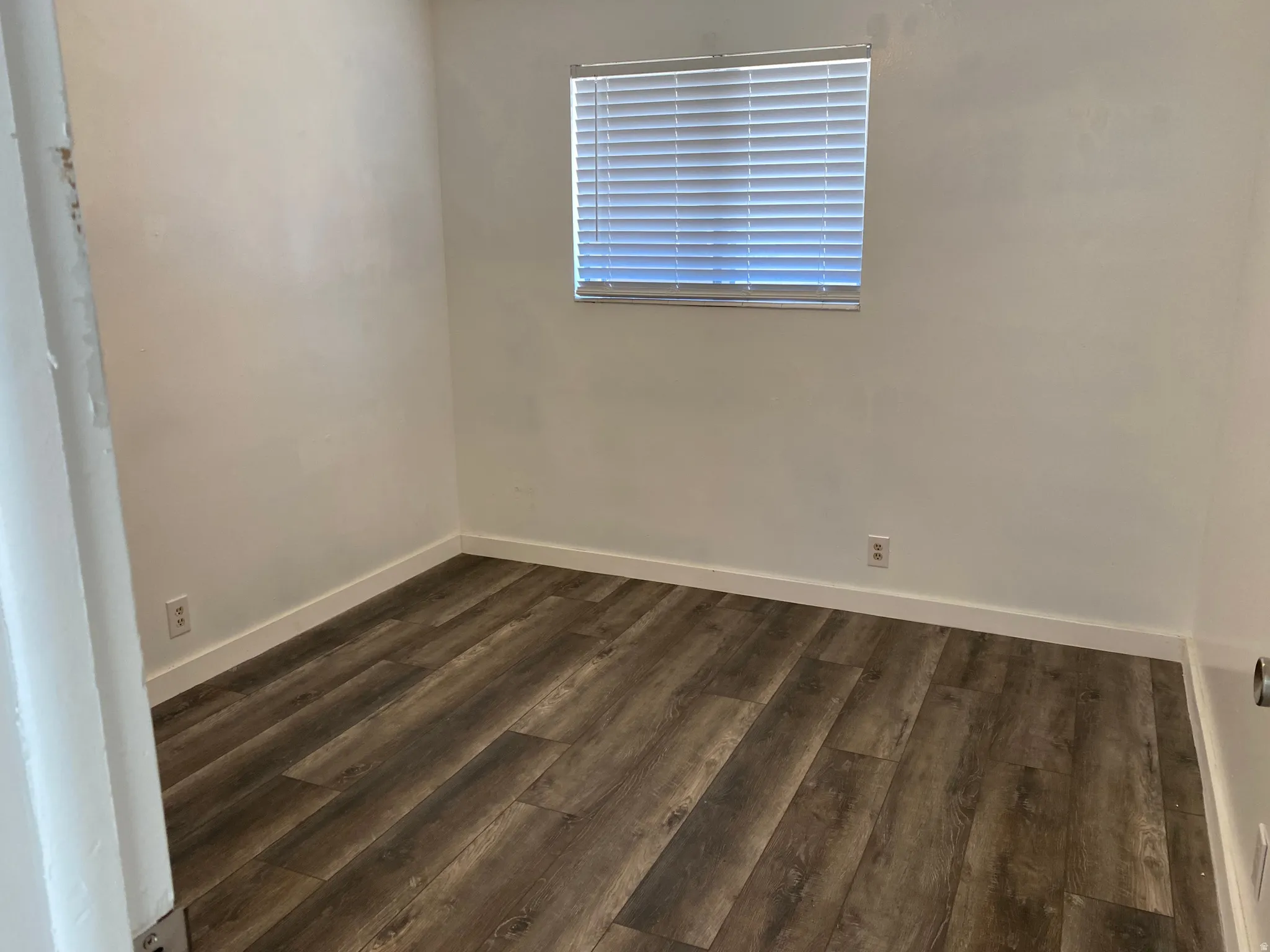 Spare room with dark wood-style floors and baseboards