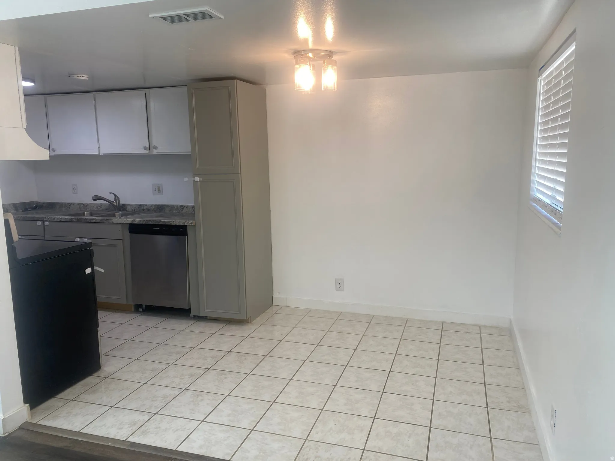 Kitchen featuring gray cabinetry, dishwasher, and light tile patterned flooring